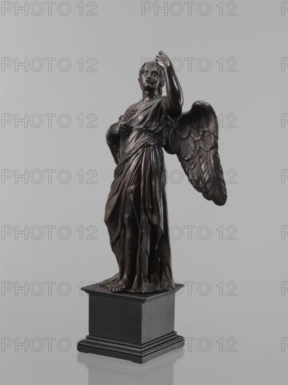 Statue - Angel, Renaissance style, 16th century. Figure of a standing angel with his left hand raised, the other raised to chest height, which originally contained a cross or an element of the Arma Christi. Square wooden base with profiles on the upper and lower edges, secondary. Sculpture, height 44 cm, width 12 cm, depth 12.5 cm. Creator: Szwarc, Szymon 1884-197?. Purchased 1933., A dark brown bronze statue of a winged figure stands on a black rectangular plinth against a light gray background, wearing draped robes with detailed folds and bare feet visible at the base, one arm raised and the other held near the chest, with textured feathered wings extending behind and a sculpted face and hair turned slightly upward.