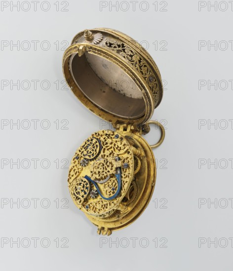 Pectoral watch, Stosch, Israel fl. 1st half of 17th century watchmaker, baroque, floral ornament, grotesques. Pectoral watch in an oval case, frame with a circular glazed cut-out, beneath which a dial with a silver ring with hour numerals. Frame decorated with an engraved tendril. Underside open-work, with a motif of a winged bust passing at the bottom into a tendril; around it a tendril motif. Openwork sides of the case with a tendril motif. Mechanism with a striking device, signed I. STOSCH. 17th century; timepiece. Height 5.3 cm, width 3.5 cm., An open ornate circular metal object with intricate filigree work, showing a hinged lid and inner mechanical components; the object appears primarily gold with accents of blue and small dark elements, set against a light gray background.