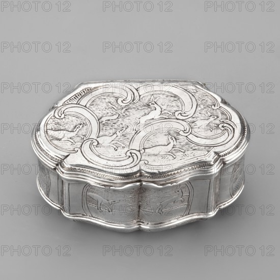 Snuffbox on an oval plan with irregular edges, vertical ribbed walls; on the lid a depiction of dogs tracking hares among channel sections; on the side walls in the reserves a dog tracking a hare, a goose, and plant ornaments. Materials/classification: scrap; function: smoking accessory. Subject motifs: animals, hares, dogs, hunting scenes, dogs tracking game, geese, plant ornaments. Maker/date: 1756–1762, Paris, France. Dimensions: height 4 cm, width 8.4 cm, depth 5.3 cm., A small decorative metal box with a scalloped oval shape sits on a flat surface; the box is silvery in color and shows engraved scenes on its lid and sides that include stylized animals and swirling curved patterns, with areas of smooth reflective metal and finely incised textured backgrounds. The overall palette is silver and gray, with subtle highlights and shadows giving the metal a polished appearance.