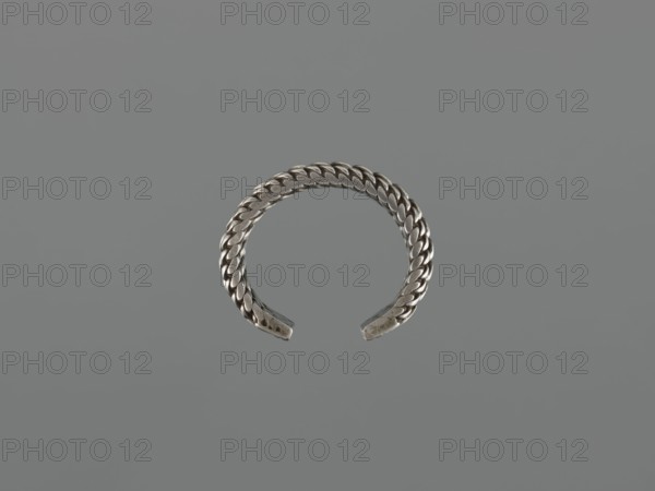 Bracelet; maker, 19th century, Middle East, Islamic art; body ornament—female hand ornament, fashion accessory; tugra motif; materials: jewelry; dimensions: height 2.5 cm, width 7.0 cm, weight 170 g., A metallic cuff-shaped object with a braided or woven pattern, shown against a uniform gray background; the object appears silver in color with darker and lighter silver tones along the braided links, and the background is a flat muted gray.