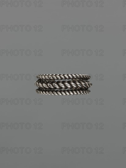 Bracelet, 19th century, Middle East, Islamic art; body/female/hand ornament, fashion accessory; tugra; materials: jewelry; dimensions: height 2.5 cm, width 7.0 cm, weight 170 g; provenance: purchase, scrap., A group of three metallic twisted rope-style rings stacked together, each ring showing a braided texture and a reflective silver-gray surface, set against a plain mid-gray background.