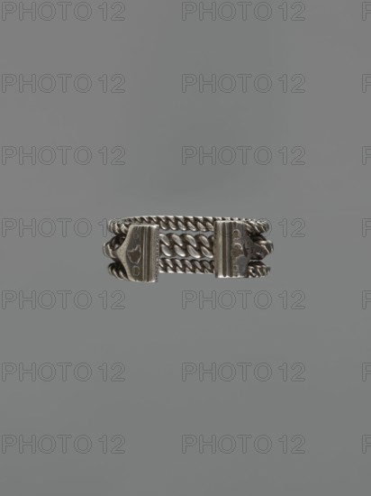 Bracelet, 19th century, Middle East, Islamic art; body/female/hand ornament, fashion accessory; tugra inscription; materials: jewelry; height 2.5 cm, width 7.0 cm, weight 170 g; provenance: purchase scrap - purchase., A metallic ring-like object centered against a smooth gray background, featuring a series of twisted and flat chain links forming a band with two rectangular end plates; the piece shows a tarnished silver-gray color with darker gray patina in recessed areas and subtle highlights on raised surfaces.