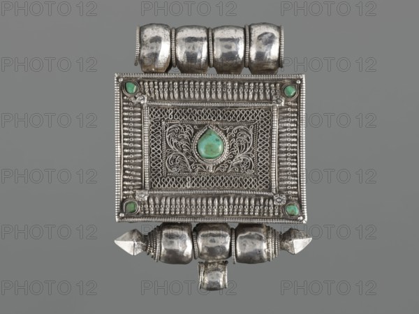 Ga'u box - fragment; maker, plant twig; jewelry; Himalayan; Tibetan Buddhist art; amulets; Tibetan; provenance, 19th century; Tibet; varia; height 11.0 cm; width 7.5 cm; weight 125 g, A rectangular silver pendant with ornate filigree and beaded borders, featuring a central teardrop-shaped green stone set within scrolling silverwork, small green stones set near each corner, a row of rounded silver beads along the top and bottom, additional cylindrical and pointed silver elements attached at top and bottom, and an overall color palette of silver and green against a gray background.