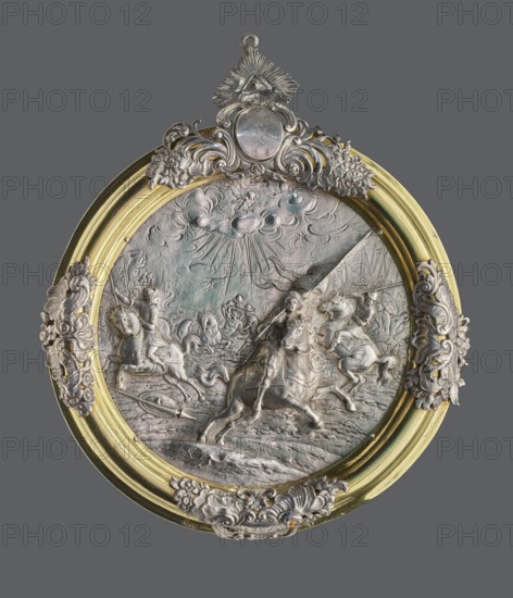 Plaque with a battle scene in a silver frame, Hardwald, Salomon fl. ca. 1700–ca. 1750 goldsmith frame, unknown goldsmith; coats of arms: Slepowron; circular, repoussé, in parts in high relief, with a representation of an episode from the Thirty Years' War. In a gilded circular profiled frame; on it four ungilded decorative elements; on the top, an oval plaque with the Slepowron coat of arms and the date 1752, above a pendant in the form of a triangular plaque with the Eye of Providence. The frame is marked on the edge with the iSHW Hardwald mark and 13. Attributed in older catalogues variously as Bavarian or Austrian work; dated 1752 inscription. Dimensions: height 26.5 cm, width 21.5 cm, weight 215 g., A circular ornate relief plaque set in a round frame with decorative flourishes shows a sculpted scene of mounted figures and horses in motion under a sky with stylized clouds and radiating beams; the central relief is predominantly metallic silver with areas of subtle greenish patina, ...