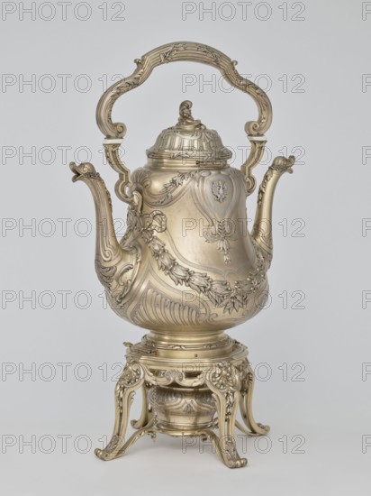 Kettle with warmer; maker: André Aucoc goldsmith; tableware, kettle; 1887–1911; France, Paris; vessel; height 39 cm, width 27 cm, depth 17 cm, A highly ornate metallic vessel with a tall curved handle and a hinged lid sits on an elaborately carved stand; the metal appears gold-toned and slightly aged, with intricate floral and scrollwork decorations covering the body, spout, handle, lid, and base. The vessel has a bulbous central body with raised decorative panels and garland motifs, a long curved spout with ornamental detailing at its tip, and a sculpted finial atop the lid. The handle is large and decorative with scroll shapes and carved accents. The stand is openwork with flowing, curved legs and matching ornamental motifs, and a small round container or burner is nestled beneath the vessel within the stand. The background is a plain light gray.
