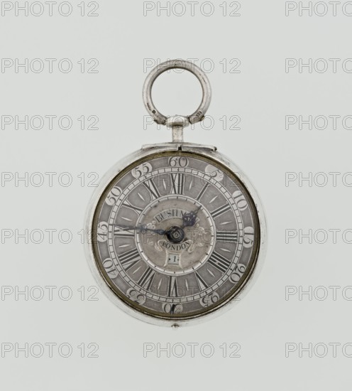Pocket watch by John Bushman 1692–1720. Silver pocket watch in three cases: outer case covered with leather, rim decorated with studded silver rosettes; middle and inner cases plain. Underside of inner case with casemaker's initial H and number 3081. Transparent lid. Silver champlevé dial with Roman numeral hour markers and Arabic minute markers in oval reserves on a matte background; central circular reserve with the watchmaker's signature on two semicircular plates reading BUSHMAN and LONDON; date window at bottom. Steel hands with openwork hour hand. Movement with plate skeleton, spring drive, worm gear, and Gall chain; spindle escapement. Gilded lower plate with an openwork English-style bun in the form of a wreath filled with acanthus tendrils and an openwork grid, connected by a mascaron mask with an openwork bun foot. Hair adjustment as a rotating silver-plated dial with scale I–VI. Engraved on the plate in italics: Jn Bushman 3081 / LONDON. Circa 1700, London, England. Timepiec...