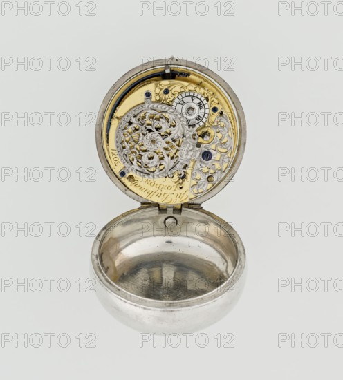 Pocket watch by John Bushman 1692–1720, c. 1700. Silver pocket watch in three cases: outer case covered with leather, rim decorated with studded silver rosettes; middle and inner cases plain. Underside of inner case stamped with casemaker’s initial H and number 3081. Transparent lid. Silver champlevé dial with Roman hour markers and Arabic minute markers in oval reserves on a matte background; central circular reserve with the watchmaker’s signature on two semicircular plates reading BUSHMAN and LONDON; date window at the bottom. Steel hands, openwork hour hand. Movement with plate skeleton, spring drive, worm gear, and Gall chain; spindle escapement. Gilded lower plate with an openwork English-style bun in the form of a wreath filled with acanthus tendrils and an openwork grid, connected by a mascaron mask with an openwork bun foot. Hair adjustment is a rotating silver-plated dial with scale I–VI. Engraved on the plate in italics: Jn Bushman 3081 / LONDON. Made in London, England. Tim...
