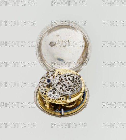 Pocket watch by John Bushman 1692–1720, silver pocket watch in three cases. Outer case covered with leather, decorated on the rim with studded silver rosettes; middle and inner cases plain; underside of the inner case stamped with the casemaker's initial H and the number 3081. Transparent lid; silver champlevé dial with Roman numeral hour markers and Arabic minute markers in oval reserves on a matte background; central circular reserve with the watchmaker's signature on two semicircular plates reading BUSHMAN and LONDON; date window at the bottom. Steel hands with an openwork hour hand. Movement with a plate skeleton, spring drive, worm gear, and Gall chain; spindle escapement. Gilded lower plate with an openwork English-style bun in the form of a wreath filled with acanthus tendrils and an openwork grid, connected by a mascaron mask with an openwork bun foot. Hair adjustment is a rotating silver-plated dial with a scale I–VI. Engraved on the plate in italics: Jn Bushman 3081 / LONDON....