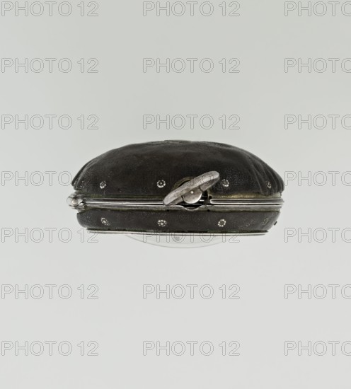 Pocket watch by John Bushman 1692–1720. Silver pocket watch in three cases: outer case covered with leather, rim decorated with studded silver rosettes, middle and inner cases plain; underside of inner case stamped with casemaker's initial H and number 3081; transparent lid. Silver champlevé dial with Roman numeral hour markers and Arabic minute markers in oval reserves on a matte background; central circular reserve with the watchmaker's signature on two semicircular plates reading BUSHMAN and LONDON; date window at the bottom. Steel hands with openwork hour hand. Movement with plate skeleton, spring drive, worm gear, and Gall chain; spindle escapement. Gilded lower plate with an openwork English-style bun in the form of a wreath filled with acanthus tendrils and an openwork grid, connected by a mascaron mask with an openwork bun foot. Hair adjustment via rotating silver-plated dial with scale I–VI. Engraved on the plate in italics: Jn Bushman 3081 / LONDON. Circa 1700, England. Timep...