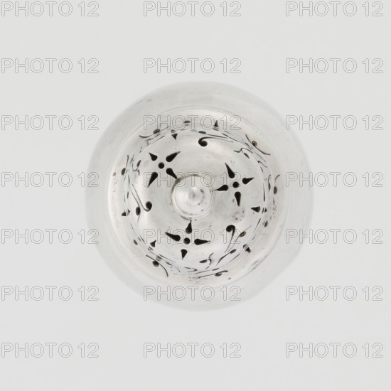 Powdered sugar bowl, powdered sugar bowl with domed openwork cover topped with a finial. Maker: Burbidge, Richard 1847–1917, goldsmith. Seller: Harrod's Stores Ltd London, fl. from 1849. Pear-shaped powdered sugar bowl on a circular profiled foot, with a domed openwork cover. Edge of the foot and the top rim decorated with astra gal ornament. Function: sugar vessel. Date: 1913–1914. Place: London, England, Great Britain. Materials/technique: openwork. Dish. Height 15 cm; diameter 5.9 cm; weight 152 g., A circular metallic object viewed from above with a domed center and a pattern of teardrop and curved cutouts arranged in a radial design, the surface showing subtle scratches and small dark spots; the predominant colors visible are silver, gray, and black, set against a pale off-white background.