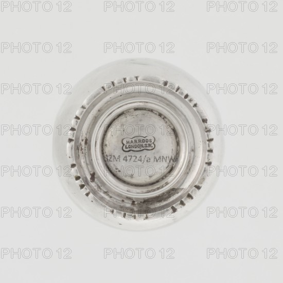 Powdered sugar bowl, pear-shaped on a circular profiled foot, with a domed openwork cover topped with a bowl. The edge of the foot and the top rim decorated with astargal. Openwork, sugar vessel, dish. Maker: Harrod's Stores Ltd; maker goldsmith: Richard Burbidge 1847–1917. Purchase provenance: scrap — purchase. Date: 1913/1914. Materials: unspecified. Dimensions: height 15 cm; diameter 5.9 cm; weight 152 g. Location: London, England., A round metallic object viewed from above with a central recessed circular area surrounded by concentric raised rings and a scalloped edge; the surface shows areas of tarnish and slight scratches. The visible colors are silver, gray, and hints of darker gray.