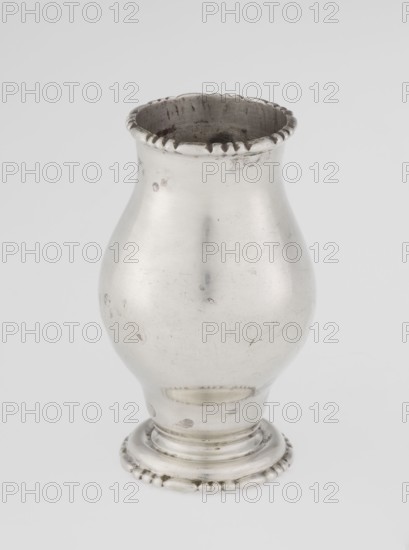 Powdered sugar bowl, pear-shaped powdered sugar bowl on a circular profiled foot, with a domed openwork cover topped with a bowl. The edge of the foot and the top rim decorated with astargal. Openwork, sugar vessel, astargal ornament. Maker: Richard Burbidge 1847–1917, goldsmith/Managing Director, 1913/1914, London, England. Dish. Height 15 cm, dia. 5.9 cm, weight 152 g., A single metallic vessel with a bulbous body tapering to a narrower neck and flared rim, showing a scalloped decorative edge at the top and a rounded pedestal base with a beaded border; the surface displays small dents and scratches and areas of darker tarnish. The visible colors are silver, gray, and darker gray tones.
