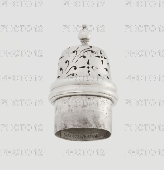 Powdered sugar bowl, pear-shaped on a circular profiled foot, with a domed openwork cover topped with a bowl. Edge of the foot and the top rim decorated with astargal. Openwork, sugar vessel; dish. Maker: Burbidge, Richard 1847–1917, goldsmith. Date: 1913/1914. Materials/technique: scrap; purchase provenance. Dimensions: height 15 cm, diameter 5.9 cm, weight 152 g., A metallic object with a rounded top and a finial sits against a pale background; the top section has decorative cutout patterns and a smooth band separating it from a cylindrical lower section that shows surface scratches and tarnish. The visible colors are silver, gray, black from the cutouts and tarnish, and a light off-white background.