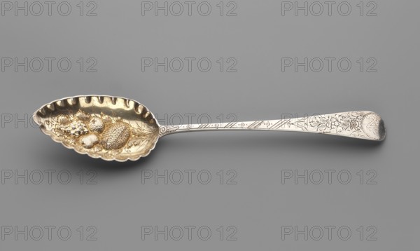 Jam spoon by John Fisher fl. 1793–ca.1810, silver; scoop with fluted edges, repoussé fruit decoration inside; flat handle widening toward the rounded, downward-curving end, engraved with floral motifs and a circular reserve engraved with monogram ER. Dated 1808/1809, London, England. Cutlery; height 22.3 cm, scoop width 4.7 cm, weight 60 g., A decorative spoon lies horizontally on a plain background, showing a scalloped bowl with a textured interior that includes raised fruit-like shapes; the bowl has a warm golden hue while the handle is a cooler silver tone with engraved floral and linear patterns, and the overall image also shows shades of gray in the backdrop.