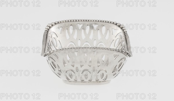 Openwork basket by Steinhart & Co Birmingham, London; goldsmith, merchant; fl. 1897–1930. Openwork silver rectangular basket with a raised edge on the longer axis; edge bordered with a pearling ribbon. Openwork forms a composition of elongated ovals and arcades; geometric ornaments and pearling ornament. Date: 1910/1911. Place: Birmingham, England, Great Britain. Function: vessel. Dimensions: height 7.3 cm, width 9.6 cm, depth 6.7 cm; weight 40 g., A metallic decorative bowl with an openwork pattern and a beaded rim sits centered on a plain light background; the bowl shows a repeating cutout design around its sides and a curved square shape with rounded corners, and the visible colors are silver and light gray.