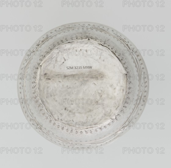 Bowl, maker: William I Sumner fl. 1773–ca. 1807, goldsmith; circular, bulging vessel with flat bottom and flared upper edge; decorated on the belly with a wide band of relief ornament of acanthus leaves and flowers; materials: presumably metal; styles: Empire, Georgian, George III; ornament: acanthus leaves, acanthus ornament, relief decoration; date: 1804/1805; place: London, England, Great Britain; dimensions: height 8 cm, diameter 11.5 cm, weight 145 g; provenance unknown., A round metallic bowl viewed from above with a hammered and slightly uneven surface showing a weathered, matte silver color. The rim and upper sides feature a decorative band of small punched indentations forming a repeated pattern, also in silver. The interior center is flatter and shows areas of subtle scratches and scuffs in silver and gray tones. The overall background is a pale, neutral gray.