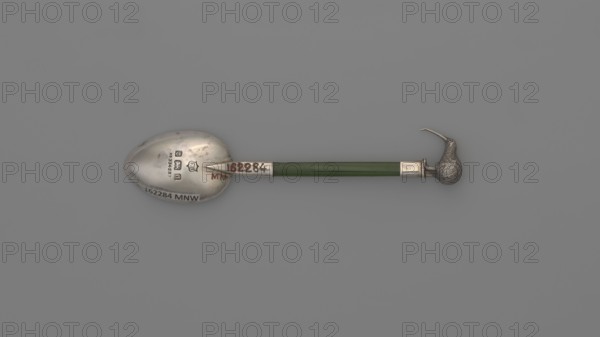 Souvenir spoon, FH goldsmith; Birmingham; fl. ca. 1903–1904. Souvenir spoon with an oval scoop, with a flat jade handle set in a silver sleeve, topped with a silver figurine of a full-plastic kiwi bird. New Zealand fauna, birds, kiwi bird. Cutlery. Height 10.8 cm, width 2.3 cm. Possible date: 1903/1904; place of origin: Birmingham, England., A horizontal object resembling a spoon with a metallic rounded bowl at one end and a sculpted bird head at the other is set against a solid gray background; the handle between them is a glossy green rod with metallic fittings near each end, the bowl and fittings show a silver-gray metallic color with darker tarnished spots, and the bird head is textured silver-gray with a long thin beak.