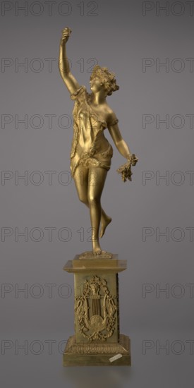 Candlestick, lyre iconographic, swans iconographic, 19th century, Paris, France, lighting, height 54 cm, A gold-colored statue of a woman posed on one foot atop an ornate rectangular pedestal, the woman shown mid-step with one arm raised and the other holding a small bunch of objects, wearing a draped garment with textured trim and a wreath-like headpiece, her hair styled and facial features visible; the pedestal is decorated with raised ornamental motifs and relief designs and rests on a stepped base; the background is a uniform gray.