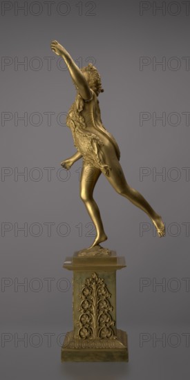 Candlestick, lyre and swans iconography, 19th century, Paris, France, lighting, height 54 cm, A gold-colored metallic sculpture of a person captured mid-stride on a decorated pedestal, shown against a smooth gray background. The figure has textured hair and wears a draped, fur-like garment, with one arm raised upward and the other extended slightly backward. The exposed skin areas of the figure, including the legs and feet, share the same gold tone as the garment. The pedestal is also gold-toned and features ornate floral relief decoration and a stepped base with patterned edges. The overall color palette is gold and gray.