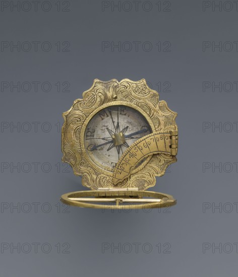 Equatorial sundial by Andreas Vogler ca. 1730–1800. Augsburg-type circular sundial with a wavy edge. Inside the case is a compass with a hinged hour circle and an arched hinged arm marked with geographical latitudes. Rim engraved with C-shaped sections and stylized acanthus leaves. Underside of the compass case engraved: Eleva. Poli. / Corfu 39 Lyon 45 /' Berlinn 53 Cadiv 36 / Lisabon 39 Paris 48 / Colln 521 Reval 61. Made in Augsburg, Germany, third quarter of the 18th century; measuring instrument., A decorative circular object with an ornate scalloped outer edge in a gold color sits open against a gray background, revealing an inner circular face with a central star-shaped motif and a needle-like pointer in dark color; the gold-colored outer rim is engraved with flowing patterns and a hinged semicircular gold element crosses part of the inner face, showing engraved markings that are not described, while a thin gold ring lies open below the main piece.