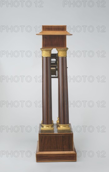 Mantel clock by Alexandre Pertrand fl. ca. 1840. Four-column portico form on a cuboid base and counter-base; boxwood inlays on the front of the cornice and base with a rhombus rosette and a tendril on both stymons; gilded bronze bases and capitals. Suspended movement with a silver dial with Roman numerals and two keyholes hanging between the columns. Gilded bronze frame with shells surrounds the clock. Oak construction with rosewood facing and light wood insets. Circa 1840, Paris, France. Timepiece; height 47 cm, width 21 cm., A vertical wooden pedestal composed of a rectangular base and a stepped platform supporting a small shelf, connected by a group of tall cylindrical columns with decorative capitals and bases; the piece shows a polished dark brown wood grain with lighter brown inlay lines and golden metallic accents on the column capitals and bases, set against a pale gray background.