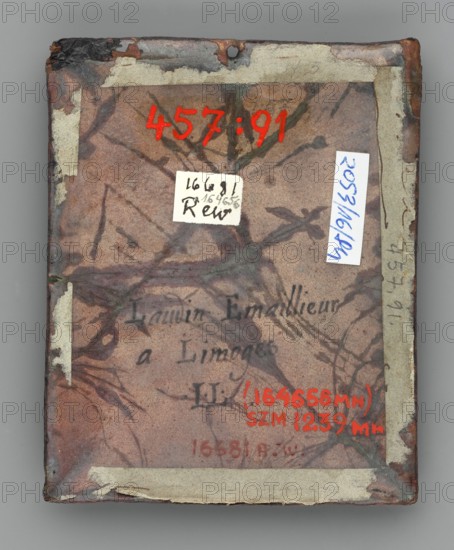 Rectangular enamelled plaque with a medallion depicting Saint Ignatius of Loyola founder of the Jesuit Order in a richly decorated dalmatic, his head haloed, holding an open book inscribed AD MAIORE DEI GLORIAM on one page. He gazes upward at a cloud of flames inscribed HS, tears streaming from his eyes. The image is framed by a circular band with plant motifs in the corners palmette. Inscription below: S IGNATIUS DE LOIOLA II. 4th quarter of the 17th century, Limoges, France. Dimensions: height 10 cm, width 8 cm. Maker: Jacques Laudin ca. 1663/8–1729, enameller., The image shows a rectangular object with worn edges and a hole near the top center, covered in aged, mottled material with marbled vein-like patterns in shades of brown, tan, green, and dark gray; there are several small pieces of adhesive tape or paper remnants along the borders in off-white and beige, and a few small labels or stickers affixed on the surface in white and light blue; bright red paint marks appear prominentl...