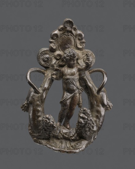 Door knocker with a figure of Bacchus, attributed to the circle of Nicolo Roccatagliata, Renaissance style, bronze door fittings. Depicts Bacchus in the center with two lions with raised torsos at either side. Variant identified as Venetian, late 16th century, in the style of Niccolò Roccatagliata; comparable knockers include a Neptune knocker from early 17th-century Venice. Door fitting, height 22 cm, width 16 cm., A small sculptural object in dark brown and bronze tones depicts a cherubic child standing with one arm raised and the other extended, draped in a short cloth, framed by an ornate, curling backdrop with scroll-like motifs; the base shows a textured surface with a pair of stylized animal heads with curled manes, and two curved handles extend from the sides, all set against a neutral gray background.