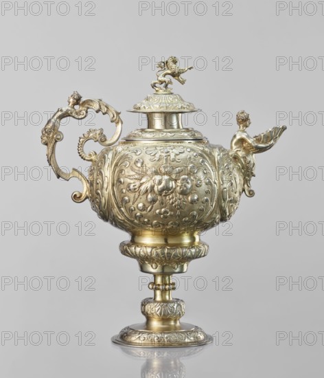 Water tincture, Schweiger, Matthias fl. ca. 1623–1635 goldsmith; author; herms decorative elements; lions; flowers ornament; fruit ornament; acanthus ornament. Jug with a spherical belly decorated with repoussé bouquets of flowers and fruit in acanthus reserves; on the side a spout in the shape of a female half-figure holding a conch; on the axis a plastic handle formed of channel sections connected by a winged herm of a woman. The cover is topped with a plastic lion standing on its hind legs. 1630–1635; Augsburg, Germany. Vessel; height 28 cm, width 14 cm, depth 30 cm., A decorative metallic vessel with a shiny golden surface rests against a pale gray background, featuring an ornate rounded body decorated with raised floral and scrollwork patterns, a curved ornate handle with scrolling motifs on one side, and a spout shaped with a small human-like figure holding a shell on the other; a domed lid topped by a small animal-like figurine sits on the top, and the vessel stands on an elabor...