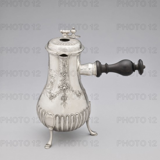 Chocolate jug by Edme-Pierre Balzac fl. 1739–1781, goldsmith. Pear-shaped chocolate vessel supported on three legs, with a small spout and a hinged lid featuring a circular opening and a sliding circular cover. The lower part of the belly is decorated with vertical curls; the upper part with repoussé garlands and an oval reserve. France, Paris, 1764–1765. Vessel: height 26 cm, width 24 cm, depth 13.5 cm. Purchased in 1883 as vieux Paris for 500 francs., A single metal pot with a rounded base and a lid sits on three curved legs, showing ornate engraved floral and scroll patterns on its body and a ribbed lower section; a dark wooden turned handle extends horizontally from one side, and the lid has a small decorative finial and a hinged opening. The visible colors are silver and dark brown against a light gray background.