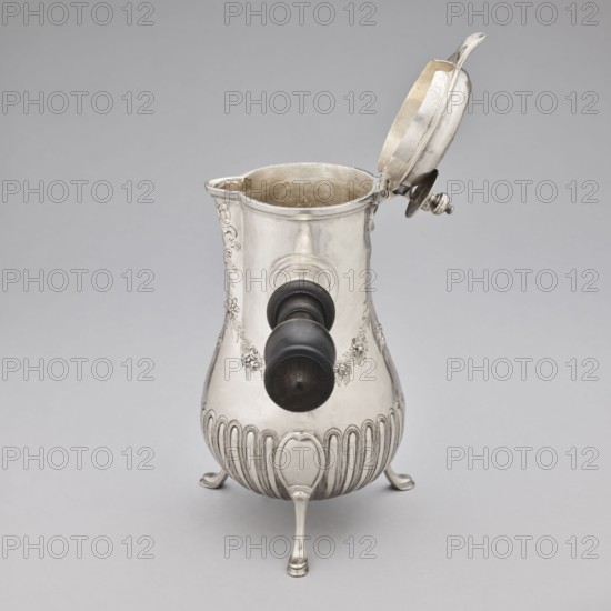 Chocolate jug by Edme-Pierre Balzac fl. 1739–1781, goldsmith. Pear-shaped chocolate vessel supported on three legs, with a small spout and a hinged lid featuring a circular opening and a sliding circular cover. Lower part of the belly decorated with vertical curls; upper part with repoussé garlands and an oval reserve. Dated 1764–1765, Paris, France. Height 26 cm, width 24 cm, depth 13.5 cm. Purchased in 1883 as vieux Paris for 500 francs., A metallic pitcher with a hinged lid propped open, featuring a bulbous body and a short spout, standing on a group of curved legs; the surface has ornate embossed floral and ribbed decorative elements and a dark cylindrical handle attached to the side. The visible colors are silver on the metal and black on the handle, set against a light gray background.
