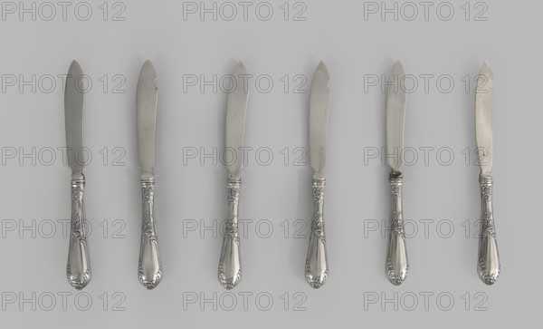 6 fruit knives, Nagalski, Adam 1862–1944 goldsmith, 1915–1920, Warsaw, Poland; cutlery; height 17.3 cm, width 1.8 cm, A row of several metal butter knives with ornate handles is arranged horizontally against a light gray background; the knives and handles appear silver and metallic with polished and slightly tarnished areas, and the background is a uniform pale gray.