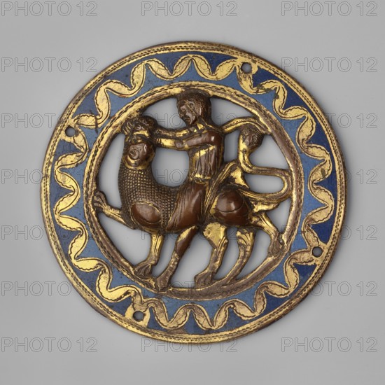 Medallion, Samson Bible, Samson fighting a lion iconography. Circular openwork medallion with an image of Samson fighting a lion. Border with a ribbon motif underlined by an engraved continuous line, straight on the inside and wavy on the outside. Enamel in two colors: light and dark blue. Geometric ornament. Plaque. 1220s–1230s, Limoges, France. Unknown provenance., A round decorative medallion with a circular frame painted blue and highlighted with gold wavy patterns; within the open center is a relief scene in brown and gold showing a human figure seated on a mythic creature with a lion-like front and a long curved tail, the rider reaching forward toward the creature's head; the medallion surface shows worn gilding and variations of brown, gold, and blue tones against a neutral gray background.