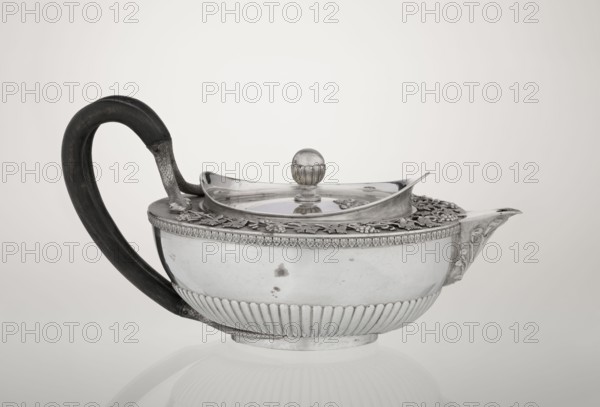 Teapot, Rundell Bridge & Rundell fl. ca. 1788–1845 goldsmith's firm; Scott, Digby & Smith, Benjamin fl. 1802–1807 goldsmith; vines, snake iconography; Pogon Ruska coat of arms; purchase provenance; tea vessel; coats of arms; tea vessel; rank crowns; princely mitre heraldry; mottos heraldry; paludamentum heraldry; acanthus leaves ornament; clasp; labry heraldry. Hemispherical, on a low cylindrical pedestal; body decorated in the lower part with radial curls, upper edge with a band of acanthus leaves; hinged lid surrounded by a raised collar with an applied vine branch with clusters; double handle of blackened wood, set in caps upper caps shaped as snake heads, lower as tails; the Czartoryski coat of arms applied on a paludament with labry and the motto Badz co sie jest. 1803/1804, London, England, Great Britain. Vessel. Height 13 cm; width 24.6 cm; depth 17.2 cm; weight 1002 g., A silver teapot with a rounded body and a fluted lower band sits on a reflective surface, featuring an ornate...