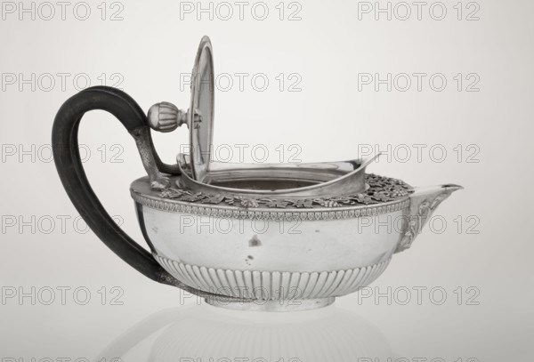 Teapot, Rundell Bridge & Rundell fl. ca. 1788–1845 goldsmith's firm, Scott, Digby & Smith, Benjamin fl. 1802–1807 goldsmiths/sellers; tea vessel, 1803–1804, London, England. Hemispherical teapot on a low cylindrical pedestal; body decorated in lower part with radial curls and at the upper edge with a band of acanthus leaves. Hinged lid surrounded by a raised collar with an applied vine branch with clusters. Double handle of blackened wood set in caps—the upper caps shaped as snake heads, the lower as tails. Applied Czartoryski coat of arms on a paludament with labry and the motto Badz co sie jest. Decoration includes vines, snake iconography, Pogon Ruska coat of arms, rank crowns, princely mitre, mottos, paludamentum, acanthus leaves, clasp, labry. Vessel; height 13 cm, width 24.6 cm, depth 17.2 cm, weight 1002 g., A silver teapot with a dark curved handle sits on a pale background; the teapot has an open hinged lid showing the inside rim and a raised decorative border around the top w...