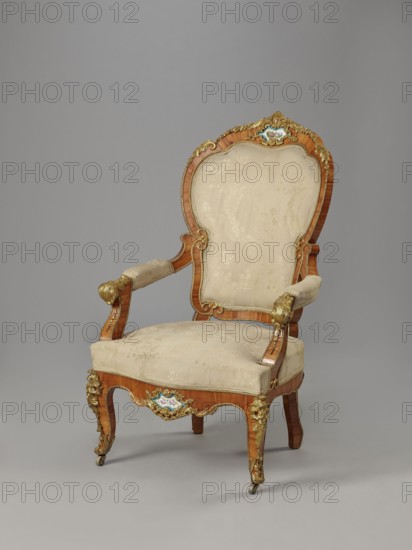 Armchair, origin unknown, rocaille ornament, neo-Rococo style; decorated with flowers, acanthus ornament, fêtes galantes, campanulas, and floral bouquets. Neo-Rococo armchair, upholstered backrest, seat, armrests, veneered with rosewood, decorated with porcelain plaques and cast brass fittings. S-shaped legs widening in the upper section cabriole, arching into a frame with a wavy outline, bulging; front ends with rollers. Armrests repeat the frame outline, on recessed, slightly S-shaped supports, topped with volutes. Backrest in the form of a symmetrical cartouche, widening upwards, framed by channel sections topped with volutes; with a clearance. Porcelain plaques painted with flowers centered on the front frame and backrest finial, each framed by a brass frame composed of rocaille, flowers, and acanthus leaves. Frame edges accented with brass strips; brass fittings include a garland at the backrest finial, volutes at the end of the armrest, acanthus plaques and slippers at the knees ...