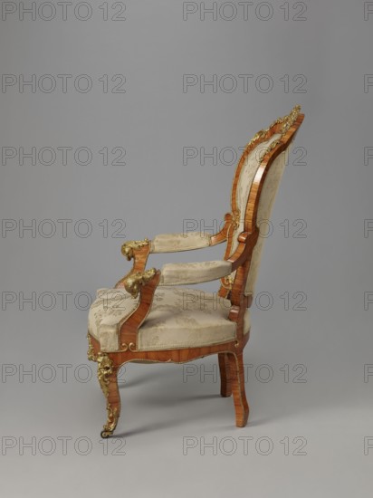 Armchair, origin unknown, neo-Rococo rocaille ornament, fetes galantes, 1850–1870, France, Veneered with rosewood; upholstered backrest, seat, armrests — upholstery non-original, on springs, with lace ribbons featuring floral bouquets. Decorated with porcelain plaques painted with flowers and cast brass fittings. S-shaped cabriole legs widening in the upper section, arching into a wavy, bulging frame terminating in rollers. Armrests repeat the frame outline on recessed, slightly S-shaped supports topped with volutes. Backrest shaped as a symmetrical cartouche widening upward, framed by channel sections topped with volutes and a clearance; porcelain plaques in center of front frame and backrest finial set in brass frames of rocaille, flowers, and acanthus. Frame edges accentuated with brass strips; additional brass fittings include a garland at the backrest finial, volutes at armrest ends, acanthus plaques and slippers at knees and feet. Function: seating unit; furniture. Dimensions: H ...