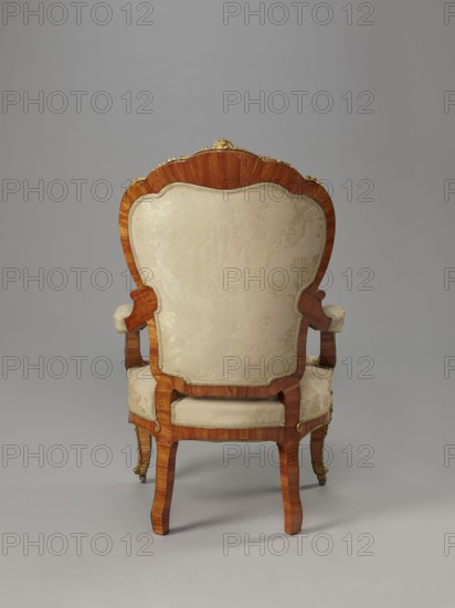 Armchair, origin unknown, rocaille ornament, neo-Rococo style; motifs: flowers, acanthus, fêtes galantes, campanulas, floral bouquets, cartouches. Neo-Rococo armchair, upholstered backrest, seat, armrests, veneered with rosewood, decorated with porcelain plaques and cast brass fittings. S-shaped legs widening in the upper section cabriole, arching into a frame with a wavy outline, bulging; front ends with rollers. Armrests repeat the frame outline, on recessed slightly S-shaped supports, topped with volutes. Backrest in the form of a symmetrical cartouche, widening upwards, framed by channel sections topped with volutes; with a clearance. Porcelain plaques painted with flowers in the center of the front frame and backrest finial, set in brass frames of rocaille, flowers, and acanthus leaves. Frame edges accented with brass strips; additional brass fittings: garland at the backrest finial, volutes at armrest ends, acanthus plaques and sabots at knees and feet. Seat upholstery on springs...