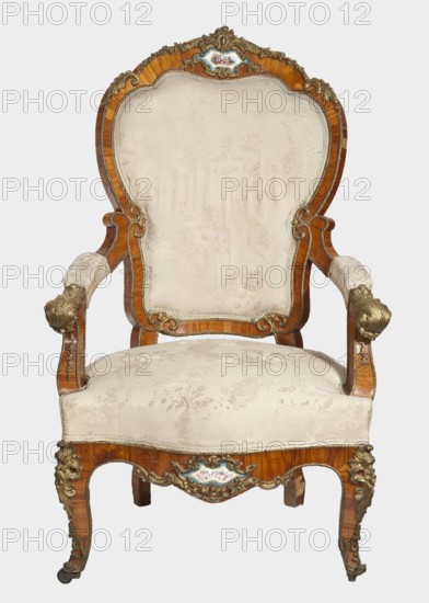 Armchair, provenance unknown. Neo-Rococo style, 1850–1870, France. Upholstered armchair backrest, seat, armrests, rose veneered, decorated with porcelain plaques and cast brass fittings. S-shaped cabriole legs widening in the upper section, arching into a wavy, bulging frame with front rollers. Armrests repeat the frame outline on recessed, slightly S-shaped supports topped with volutes. Backrest shaped as a symmetrical cartouche widening upwards, framed by channel sections topped with volutes, with a clearance. Porcelain plaques painted with flowers set in brass frames composed of rocaille, flowers, and acanthus leaves at the center front frame and backrest finial. Frame edges accented with brass strips; brass fittings include a garland at the backrest finial, volutes at the armrest ends, acanthus plaques and slippers at the knees and feet. Seat upholstery on springs; upholstery non-original, with lace ribbons featuring floral bouquets. Motifs: flowers, rocaille, acanthus, fetes galan...