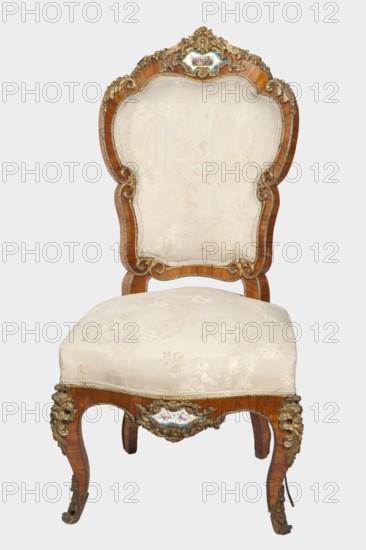Chair, origin unknown, neo-Rococo style, rocaille ornament, flowers, acanthus ornament, fêtes galantes, floral bouquets, cartouches. Neo-Rococo chair with padded backrest and seat, veneered with rosewood, decorated with porcelain plaques and cast brass fittings. S-shaped legs widening in the upper section, arching into a frame with a wavy outline and bulging form; front legs with rollers. Backrest shaped as a symmetrical cartouche widening upwards, enclosed by channel sections topped with volutes and with a clearance. Porcelain plaques painted with flowers set in the center of the front frame and backrest finial, framed by brass composed of rocaille, flowers, and acanthus leaves. Edges of the frame accented with brass moldings; knees and feet feature acanthus plaques and slippers. Seat upholstery on springs; upholstery not original, with lace ribbons featuring floral bouquets. Dated 1850–1870, France, seating furniture; height 104 cm, width 52.5 cm, depth 51 cm., A single ornate chair ...