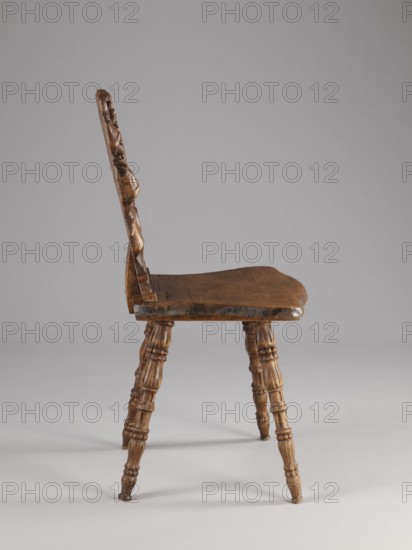 Stool, scrollwork ornament, neo-Renaissance style, cabochon ornament, ca. 1850, Warsaw place of origin?, piece of furniture, seating piece, height 90 cm, width 44 cm, depth 45 cm, A wooden chair shown in profile with a carved backrest, a contoured seat, and turned legs; the wood displays varying tones of brown with darker brown areas in places, and the background is shades of gray.