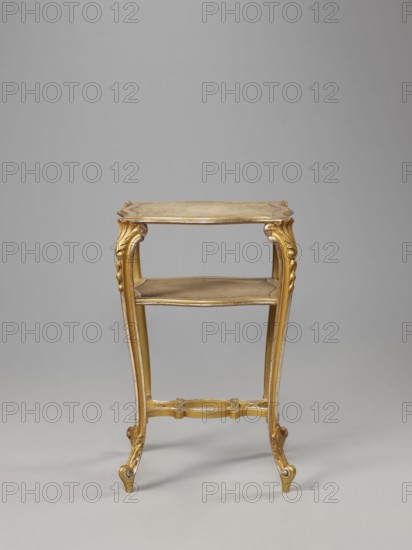 Side table, equipment of representative buildings of the Republic of Poland 1918–1939, plant decoration with acanthus ornament and volutes, neo-rococo style, 3rd quarter of the 19th century, Warsaw; furniture, table; height 77.3 cm, width 50 cm, depth 40 cm, A small ornate wooden table with a gilded finish in shades of gold and muted beige, shown against a plain light gray background; the table has a rectangular top with a slightly scalloped edge, carved decorative apron, and a lower shelf; its four slender cabriole legs are carved with scroll and acanthus motifs and end in small outward-curving feet; a carved stretcher connects the legs near the base and includes a circular decorative element at its center; the overall color palette includes gold, beige, and light brown tones.