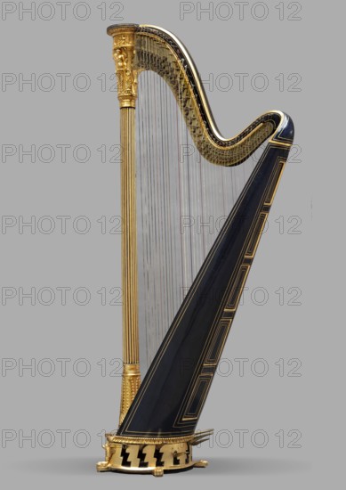 Two-stage pedal harp, Erard London ; musical instrument manufacturer ; 1792-, co-creator Erard Paris ; musical instrument manufacturer ; 1780- . Two-stage pedal harp, 43-stringed, Empire style, carved, gilded, and polychromed. The column is a fluted column topped with a capital tapering downward with applied plaster-modeled decoration: at the top, a frieze with winged figures holding straight trumpets and lyres; below, three caryatids with wings and wreaths, between them palmettes, rosettes, and pearls. The arm is S-shaped, painted indigo, with gold-painted veins. The soundboard tapers upward, rounded at the back, painted indigo, with double gilded frames, and a spruce top. The semicircular base, on low legs with carved necks, with palmettes and a female head in a wreath on the front, houses 7 brass two-step pedals for tuning and 1 single-step pedal for opening the sound holes. 1829, London. Musical instrument. Height 170.5 cm; width 44 cm; depth 80 cm., A tall ornate harp stands again...