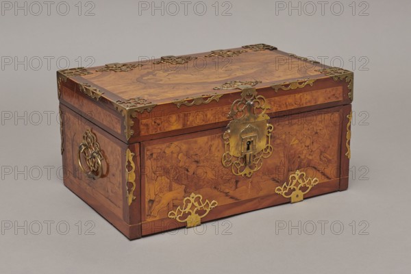 Casket, Repossession provenance. Sleigh, deer, hunters, hounds, riders. Baroque style. Cuboid case inlaid with figural scenes, with openwork brass fittings. Front wall of the body shows a deer hunt with dogs; lid has an oval field showing a sleigh drawn by a deer. Inside the body, under the chamber floor, are three drawers middle one smaller accessible after folding down the front wall. Lid contains a compartment closed with a plate on brass hinges. Fittings cut from thick brass sheet, placed on the edges of the lid and the corners of the body. Bottom and back wall fastened with strap hinges with decorative openwork finials visible from the back of the lid and at the bottom of the front wall. Mortice-type lock with two catches mounted on the bottom of the lid. Date: 1720–1740. Place of origin: Germany. Furniture; storage furniture. Dimensions: height 21.6 cm; width 42.5 cm; depth 27.4 cm., A rectangular wooden chest with a hinged lid sits on a neutral gray surface and background; the c...