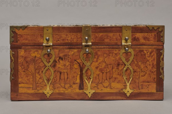 Casket, Repossession provenance. Sleigh, deer, hunters, hounds, riders. Baroque style. Cuboid case inlaid with figural scenes, with openwork brass fittings. Front wall of the body shows a deer hunt with dogs; lid has an oval field depicting a sleigh drawn by a deer. Inside the body, beneath the chamber floor, are three drawers middle smaller accessible after folding down the front wall. Lid contains a compartment closed with a plate on brass hinges. Fittings cut from thick brass sheet on the lid edges and body corners. Bottom and back wall fastened with strap hinges with decorative openwork finials visible from the back of the lid and at the bottom of the front wall. Mortice-type lock with two catches mounted on the bottom of the lid. Dated 1720–1740, Germany. Furniture — storage furniture. Dimensions: height 21.6 cm, width 42.5 cm, depth 27.4 cm., A rectangular wooden chest with warm brown and golden tones sits against a neutral background, its front decorated with marquetry showing a...