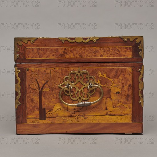Casket, Repossession provenance. Sleigh, deer, hunters, hounds, riders. Baroque style. Cuboid case inlaid with figural scenes, with openwork brass fittings. Front wall of the body depicts a deer hunt with dogs; lid shows, in an oval field, a sleigh drawn by a deer. Inside the body, under the chamber bottom, are three drawers middle one smaller accessible after folding down the front wall. Lid contains a compartment closed with a plate on brass hinges. Fittings cut from thick brass sheet placed on the lid edges and body corners. Bottom and back wall fastened with strap hinges with decorative openwork finials visible from the back of the lid and at the bottom of the front wall. Mortice-type lock with two catches mounted on the bottom of the lid. Date: 1720–1740. Place of origin: Germany. Furniture — storage furniture. Dimensions: height 21.6 cm; width 42.5 cm; depth 27.4 cm., A small rectangular wooden box sits on a neutral gray surface against a gray background, showing a front face wit...