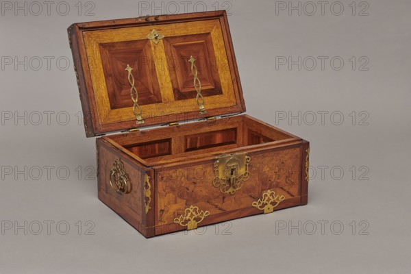 Casket, cuboid case inlaid with figural scenes and openwork brass fittings. Front shows a deer hunt with dogs; lid has an oval field depicting a sleigh drawn by a deer. Interior: under the chamber floor are three drawers middle smaller accessible after folding down the front wall. Lid contains a compartment closed with a plate on brass hinges. Fittings cut from thick brass sheet on lid edges and body corners. Bottom and back wall fastened with strap hinges with decorative openwork finials visible from back of lid and at bottom of front wall. Mortice-type lock with two catches mounted on bottom of lid. Baroque style, 1720–1740, Germany. Furniture — storage furniture. Dimensions: H 21.6 cm, W 42.5 cm, D 27.4 cm., A wooden chest with its lid open sits on a flat surface, showing a rectangular interior and paneled inner lid. The chest is various shades of brown with darker and lighter wood grain, and it has several decorative metal fittings in a yellowish metallic color on the lid, front, a...