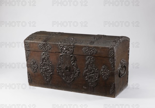 Chest, provenance unknown, plant decoration, rocaille ornament, rococo ornament, monograms, baroque style, crowns; dowry chest with a convex lid, side walls slightly tapering toward the bottom, richly decorated with openwork repoussé fittings with plant motifs, elements of rocaille and stylized acanthus. On the front of the lid, on the axis, an openwork plate with a rococo cartouche containing the date and initials 17 DEG 73. On the sides of the lid are two decoratively designed strap hinges extending into the decoration of the front wall, where the fittings create a horizontal composition composed of five asymmetrical cartouches, decreasing toward the sides. Side edges of the lid are edged with openwork bands; analogous applications in the corners of the body. The side walls feature large openwork plates. Lid boards joined with tongue-and-groove joints. 2nd half of the 18th century 1773?, Central Europe; piece of furniture, storage unit. Dimensions: height 69.7 cm, width 129.4 cm, dep...