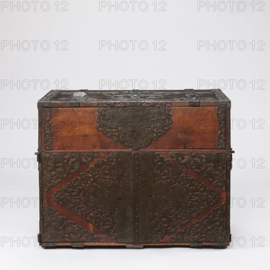Cabinet, late 17th century, Northern Germany or Poland — cuboid storage piece height 70.1 cm, width 89.2 cm, depth 55.9 cm. Cabinet with a top drawer and double doors below, richly decorated with openwork engraved fittings bearing grotesque motifs, fantastic animals, grotesques, fantastic figures, plant tendril ornament, wickerwork ornament, and male figures. Door leaves veneered inside with rosewood and ebony in geometric arrangements divided by inlaid bone veins, with figures in engraved bone signed Hippocrates on the left and Hermes on the right. Behind the doors are twelve compartments. Drawer and door locks fitted with engraved steel plates; the drawer lock blocks the left door leaf. Steel hinges., A wooden chest with a rectangular shape and a hinged top sits against a plain neutral background. The wood shows a warm brown color with visible grain, and dark metal fittings and decorative plates cover much of the front and top. The metalwork is dark brown to black and features ornate...