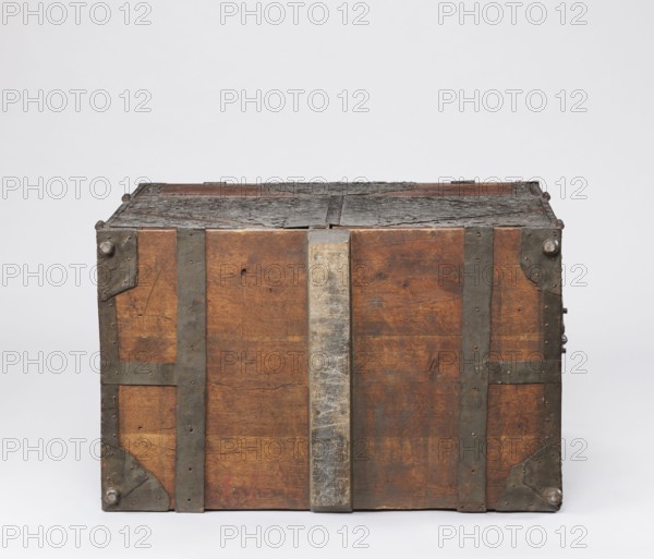 Cabinet, late 17th century, Northern Germany, or Poland, cuboid storage piece with a top drawer and double doors below, height 70.1 cm, width 89.2 cm, depth 55.9 cm. Richly decorated with openwork engraved fittings featuring grotesque motifs, fantastic animals and figures, male figures, Hermes, plant tendrils and wickerwork ornament. Door leaves veneered inside with rosewood and ebony in geometric arrangements divided by inlaid bone veins, with figures in engraved bone signed Hippocrates on the left and Hermes on the right. Behind the doors are twelve compartments. Drawer and door locks fitted with engraved steel plates; the drawer lock blocks the left door leaf. Steel hinges., A rectangular wooden chest with visible metal reinforcements and corner brackets, showing a worn and weathered surface; the wood appears brown with variations in tone and grain, the metal fittings are dark gray to black with areas of lighter gray wear, and the top shows rough, decayed dark gray material; the bac...