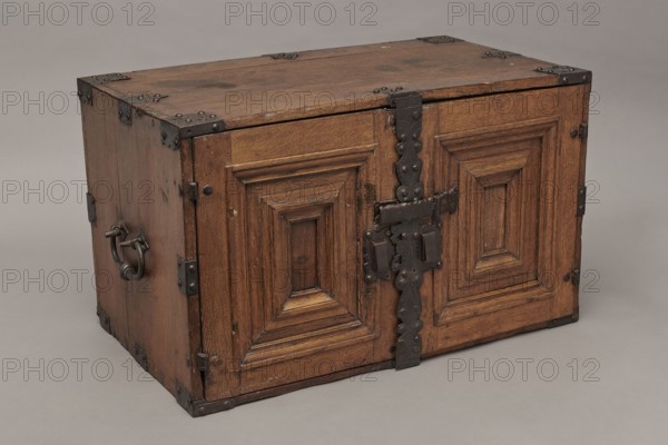 Cabinet, Baroque period, 2nd quarter of the 17th century, Gdansk. A cuboid cabinet with a boarded body, fitted with steel decorative strips, closed with double doors. Framed doors with single panels in the form of convex coffers glued at the mitre from richly profiled strips. Steel closing strip with a wavy outline; rectangular and trefoil-shaped angular fittings on the edges of the body, punched, fastened with headers. Inside, sixteen drawers arranged in five rows: two in the top row, four in each of the two middle rows, and three in each of the bottom rows. Drawer faces are framed with profiled strips; the three drawers in the middle row feature numerous internal divisions. Walls connected with exposed diagonal dovetails; back joined to top and sides with dowels. Drawers have exposed diagonal dovetail joints and nailed bottoms. Side handles are oval; drawer handles are round with rosette-shaped plates. Hinges are steel, strap-type, with a wavy outline. Both door leaves have steel mor...